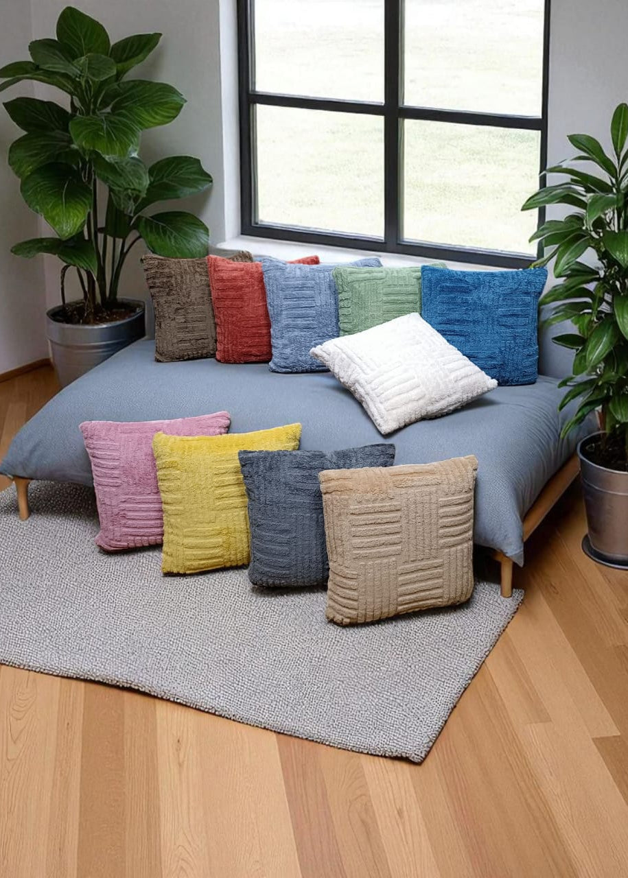 Colorful pillows on a bed in a room with plants and a window.