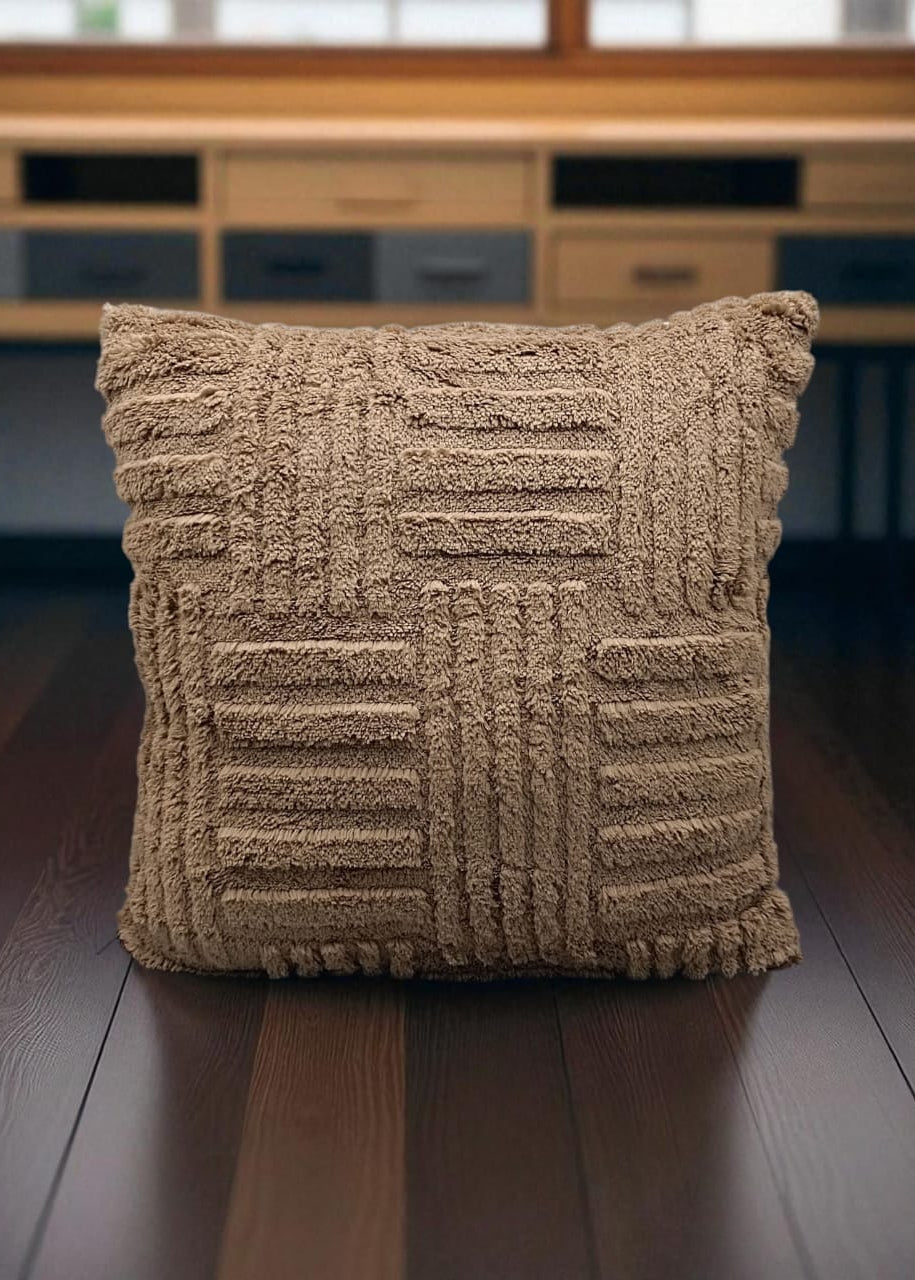 Textured brown pillow on a wooden surface with a blurred background