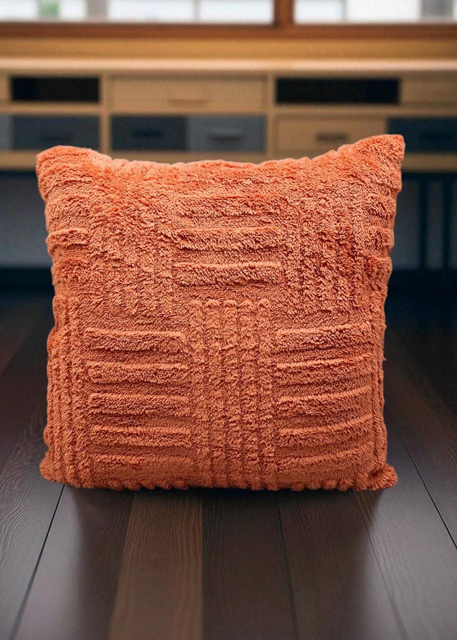 Orange textured pillow on a wooden surface with a blurred background