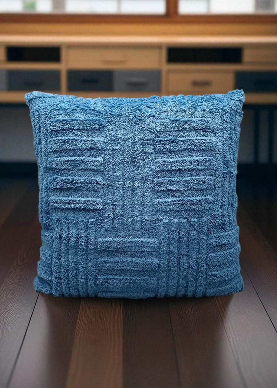 Blue textured pillow on a wooden floor with a blurred background