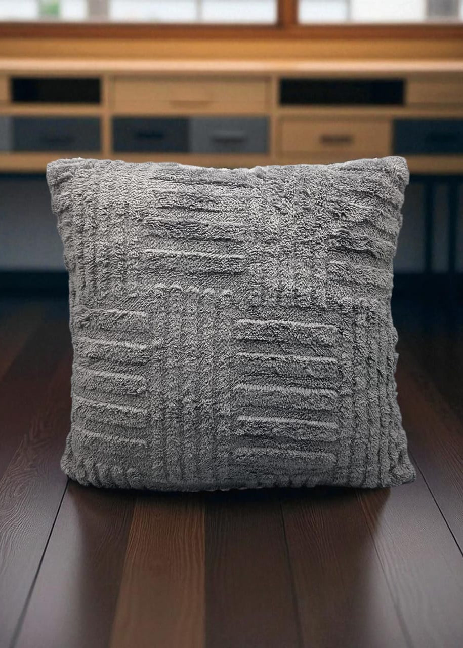 Textured gray pillow on a wooden floor with a blurred background