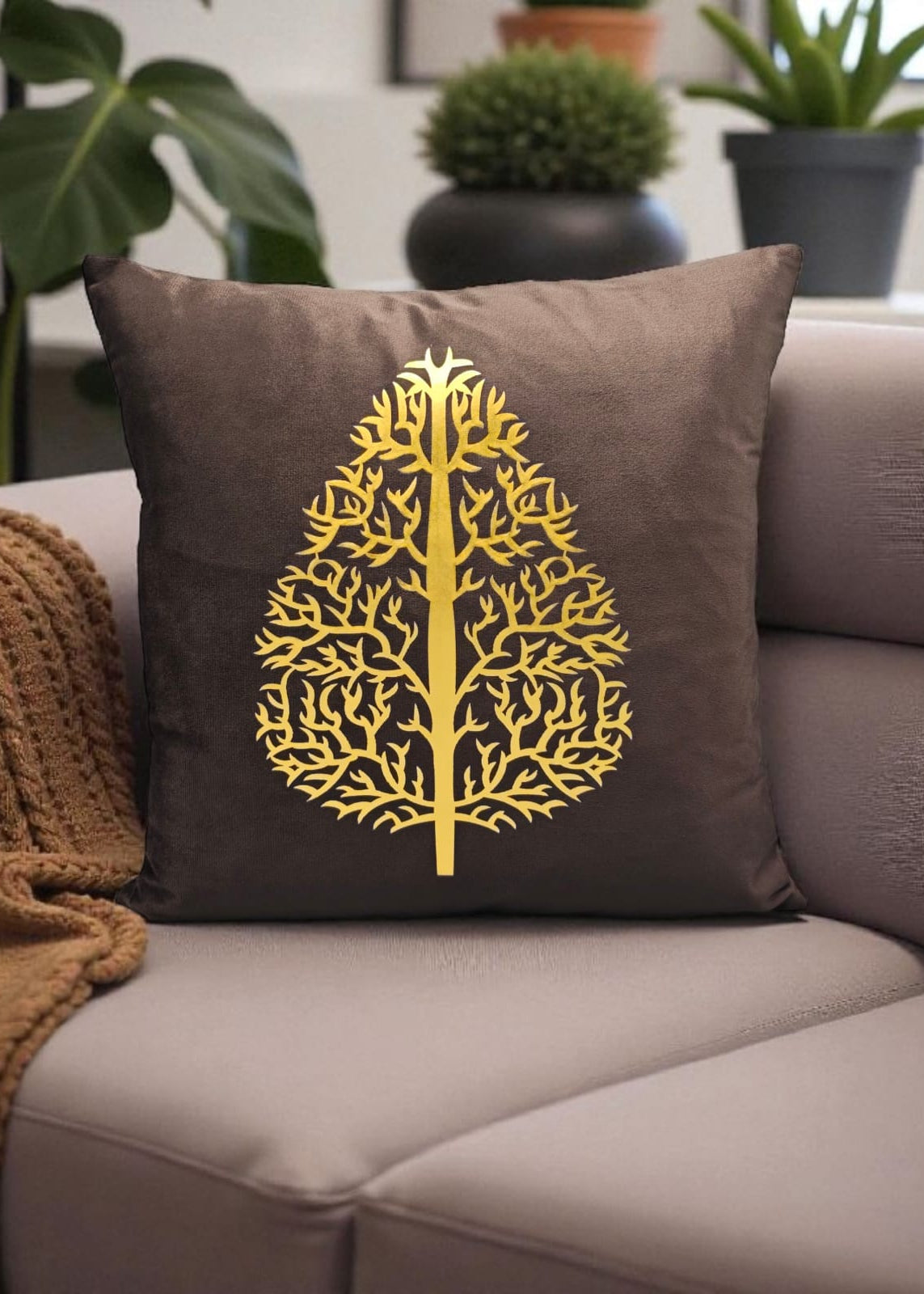 Brown pillow with a gold tree design on a gray couch
