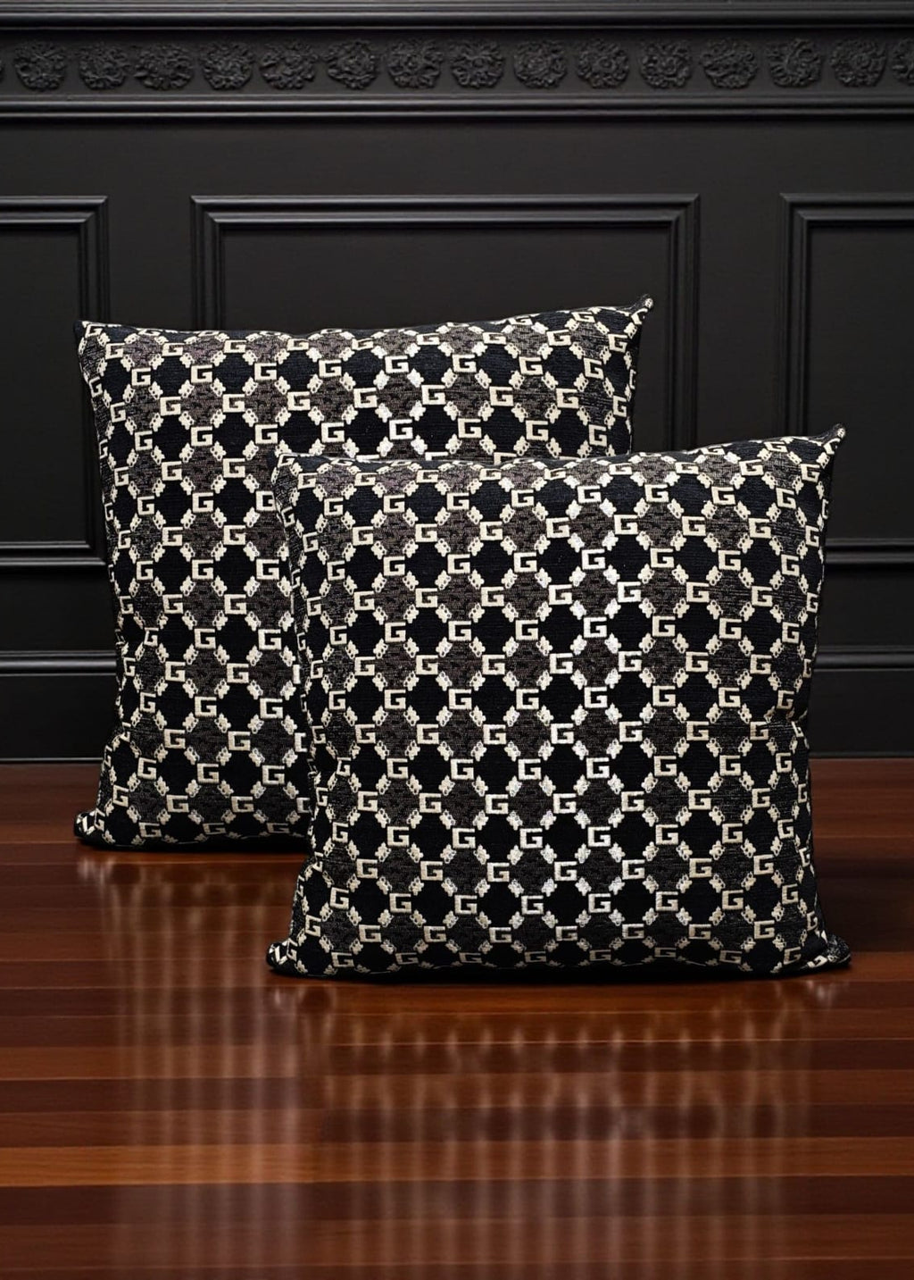 Two patterned pillows on a wooden floor with a dark wall background